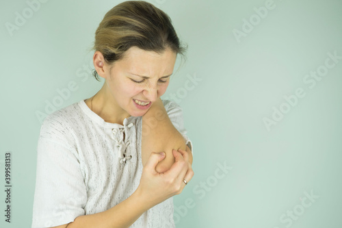 Beautiful woman holding her elbow with pain and arm ache, isolated. photo