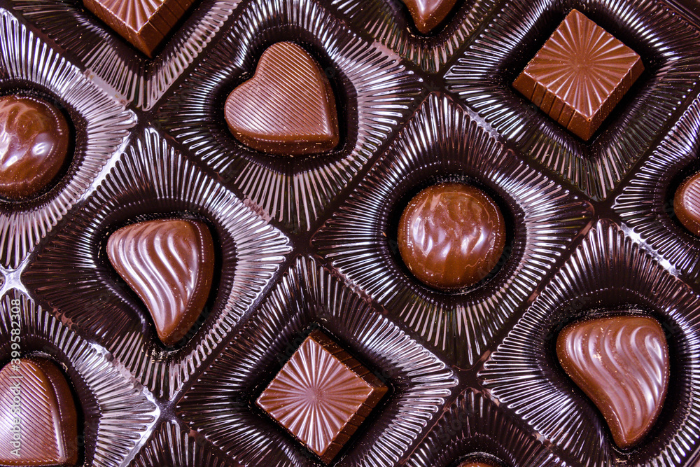 Fototapeta premium Heap of chocolate candies in a brown box. Top view