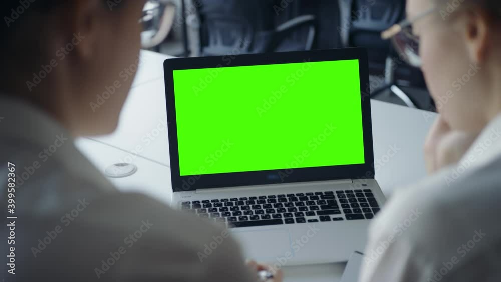 Female business women conference video call on laptop computer look at the green screen. Office person using laptop with computer green screen Distance work concept. Over shoulder close up view