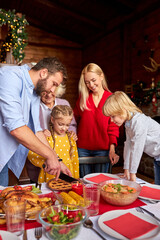 extended family carving christmas pie together, preparing table for celebration, going to have meal