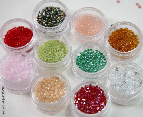 Multicolored small beads in transparent jars on a light background