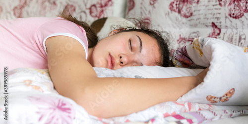 teenage brunette in purple t-shirt sleeps on large bed