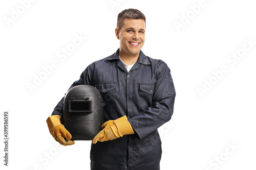 Young cheerful welder in a uniform holding a protective helmet photo