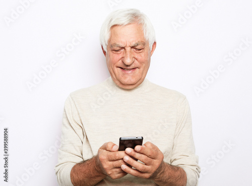 Old active man with mobile phone isolated on white background © Raisa Kanareva