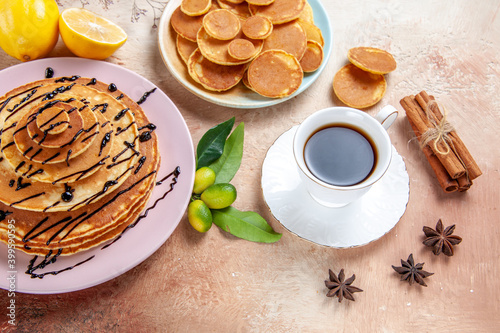 Overhead view of simple and decorated classic pancakes with fruits and cinnamon on colourful table photo