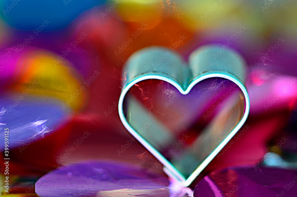 Light rays emerging from a metallic heart cookie cutter on a colorful background Light rays emerging from a metallic heart cookie cutter on a colorful background