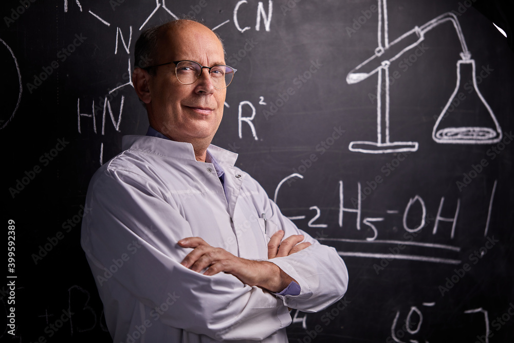 intelligent professor chemist man posing at camera, smiling. standing with crossed arms. professor at university