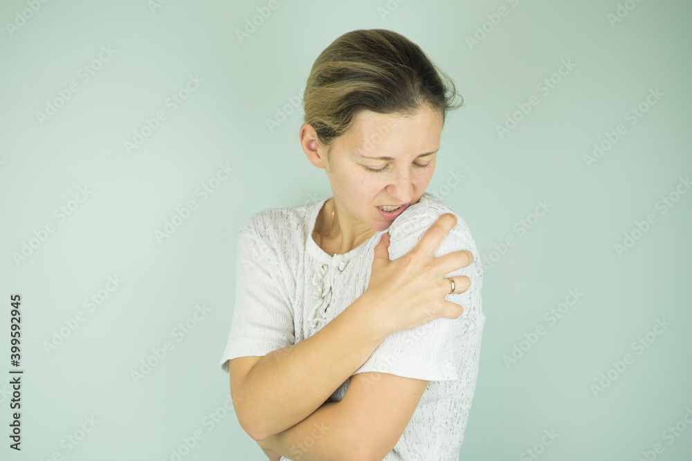 girl holding her shoulder in pain on gray background girl holding her shoulder in pain on gray background