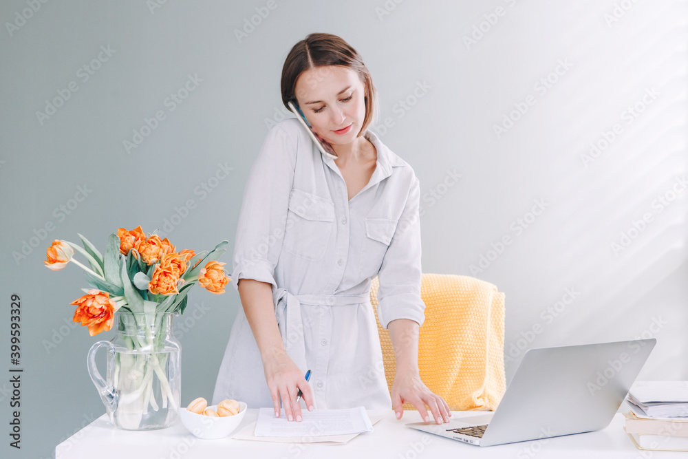 Beautiful middle age woman at desktop table working on laptop computer. Work business from home. Remote distant studying and working. Young woman talking on mobile phone. Beautiful middle age woman at desktop table working on laptop computer. Work business from home. Remote distant studying and working. Young woman talking on mobile phone.