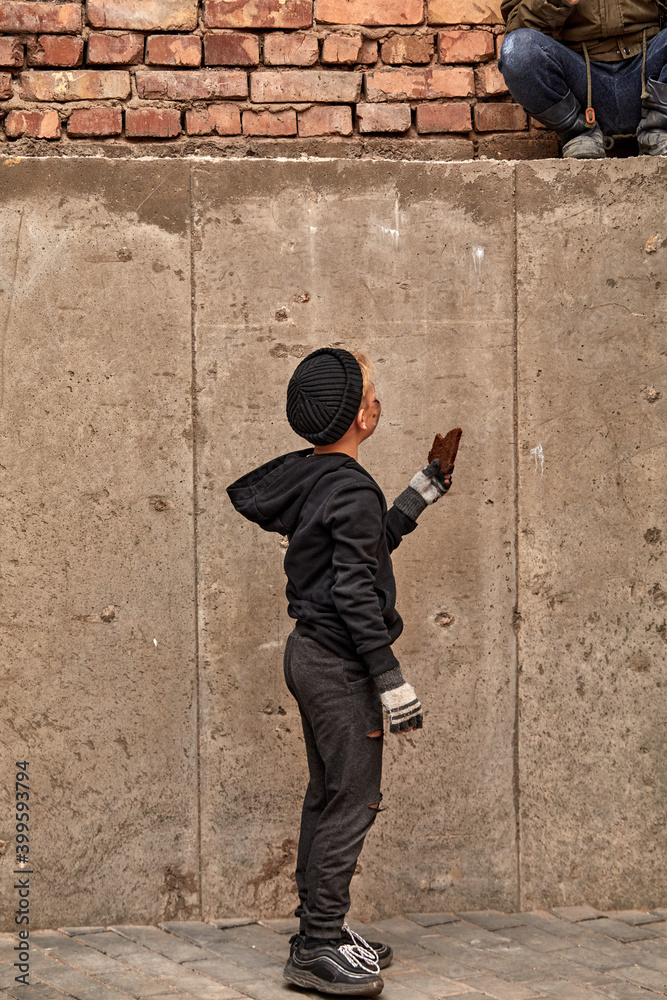 friendly child give a piece of bread to his street boy friend, street children want to eat, on city street. sharing friendly child give a piece of bread to his street boy friend, street children want to eat, on city street. sharing
