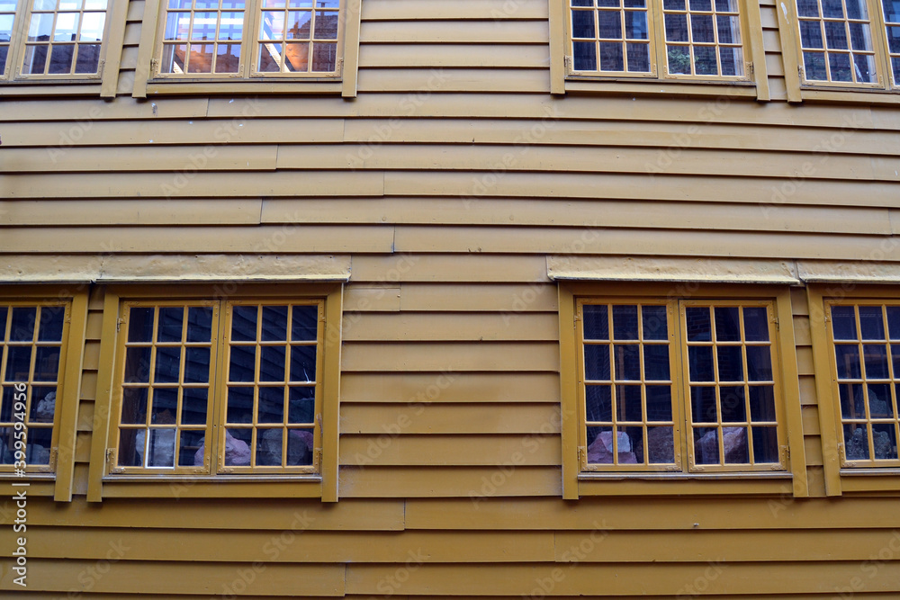 Yellow wall of an old wooden building with vintage windows, Bergen, Norway. Front view.