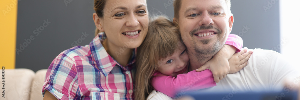 Family mom dad daughter sit in an embrace and photographed on smartphone. Family selfies for social media concept Family mom dad daughter sit in an embrace and photographed on smartphone. Family selfies for social media concept