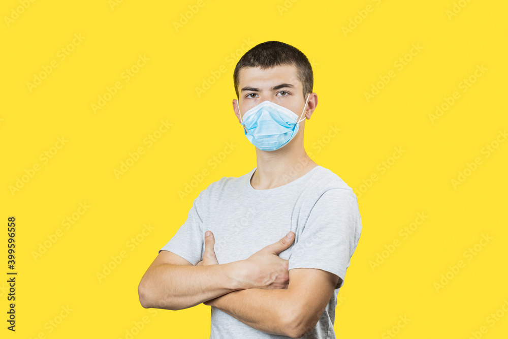 young attractive man wearing surgical flu mask and gloves to protect covid virus pandemic over yellow background. copy space. studio shot young attractive man wearing surgical flu mask and gloves to protect covid virus pandemic over yellow background. copy space. studio shot