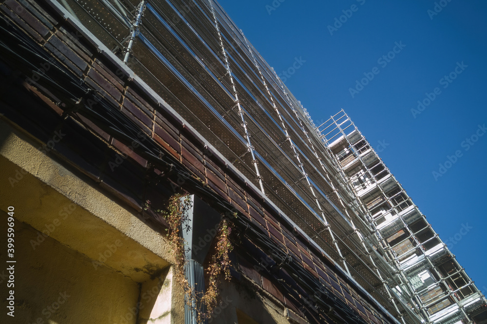 Edificio alto en obras de reforma con la fachada cubierta por andamios