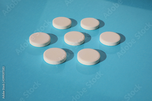 Top view of white rounded drugs isolated on blue background. Mock-up of high quality photo.