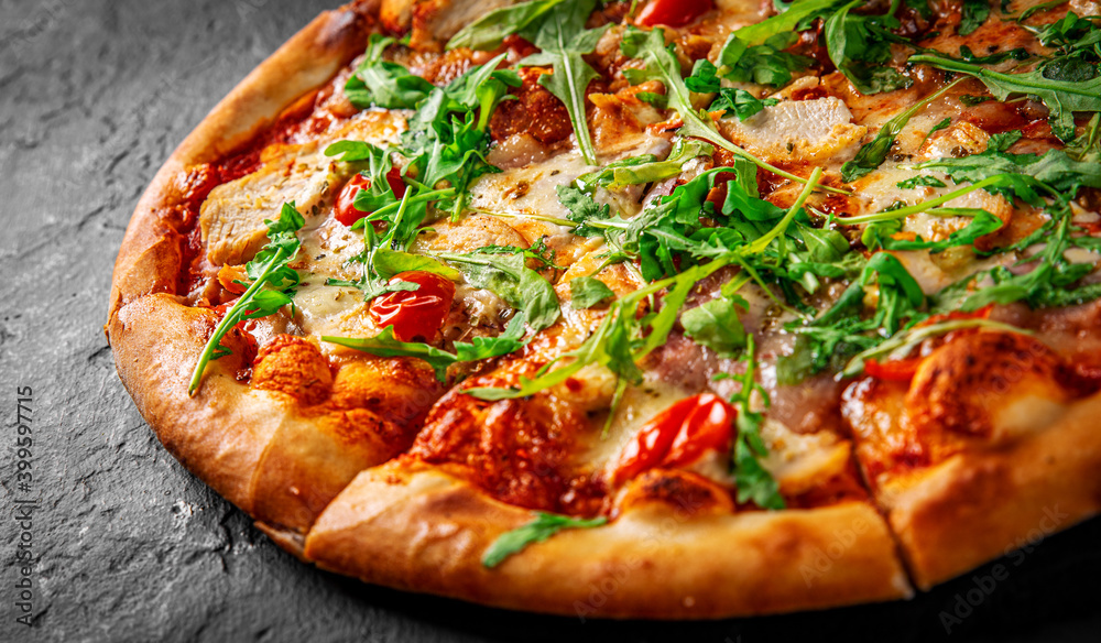 Pizza with chicken, bacon, cheese, tomato and arugula. Italian pizza on Dark grey black slate background