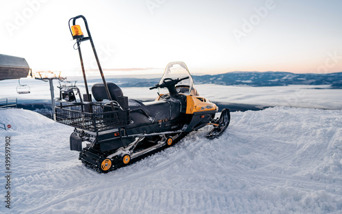 Snowmobile in the snow on the skiing hill of the ski area.ountain ski resort and winter calm mountain landscape. Winter ski resort - popular travel destination photo