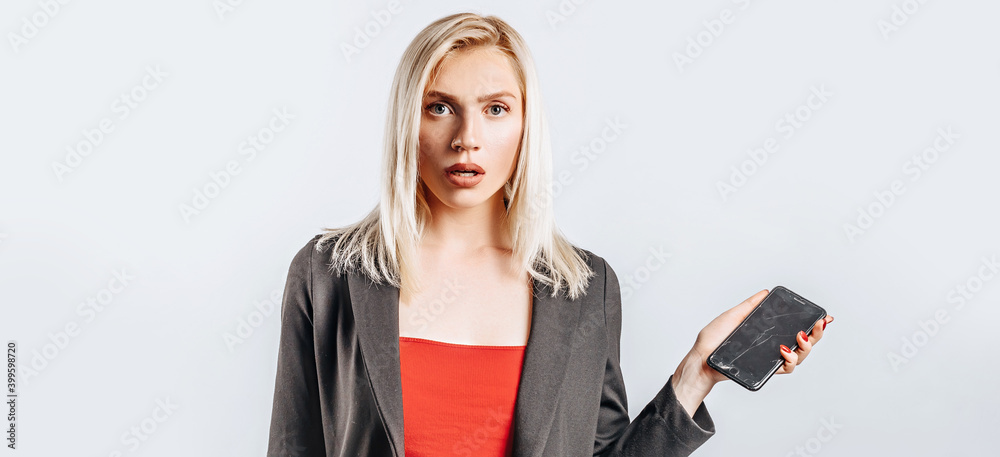Beautiful young girl unhappy and holding phone on gray isolated background Beautiful young girl unhappy and holding phone on gray isolated background