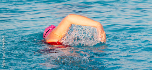 Free style swimmer in a pool lifting her right arm out of the water