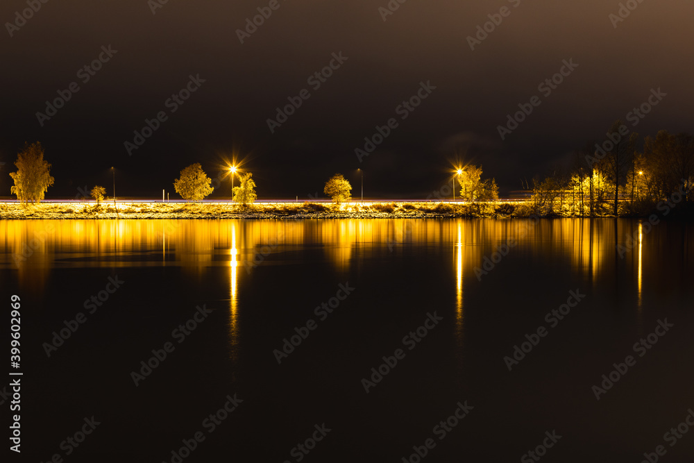 Road lighted up during night. Reflections in the surrounding water. 
