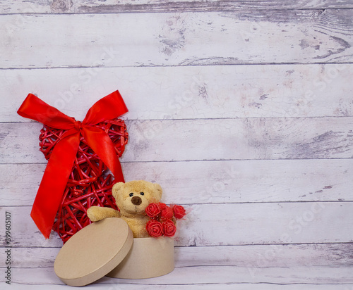 Valentine's Day. A red heart and a key bear are sitting in a packing box with flowers. Holiday. Background and texture.