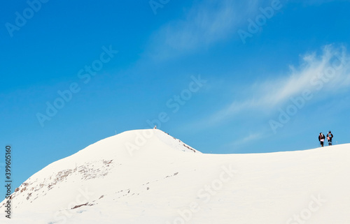 A group of hikers ascending a snowing mountain in sunny winter morning