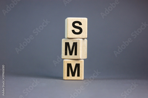 SMM symbol. Wooden cubes with word 'SMM - social media marketing' on beautiful grey background, copy space. Business and SMM concept.