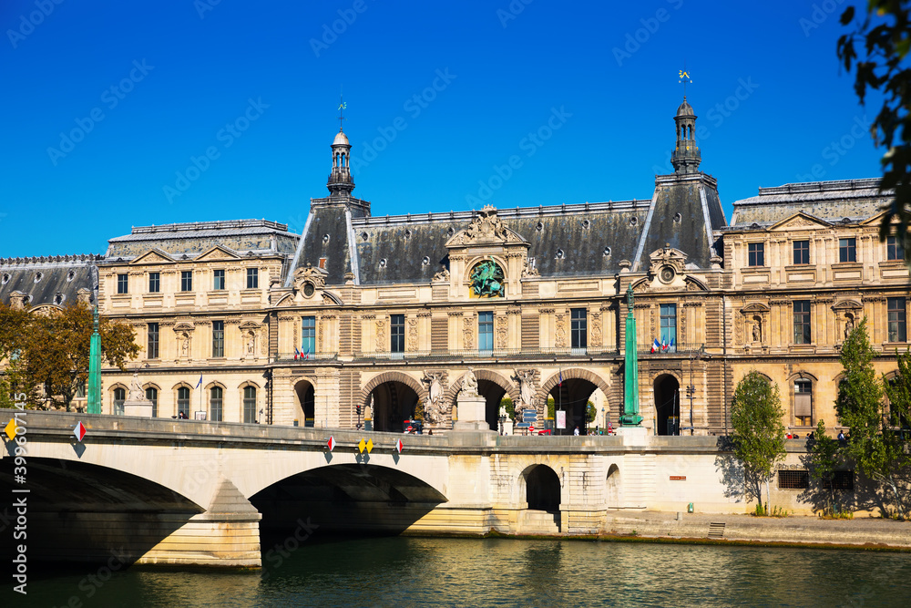 View of Pont du Carrousel across Seine river leading to arched entrance to Louvre palace courtyard, Paris, France..