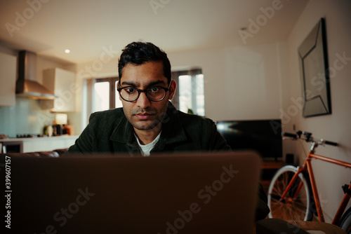 Mixed race businessman concentrating while working off digital laptop sitting at home office 