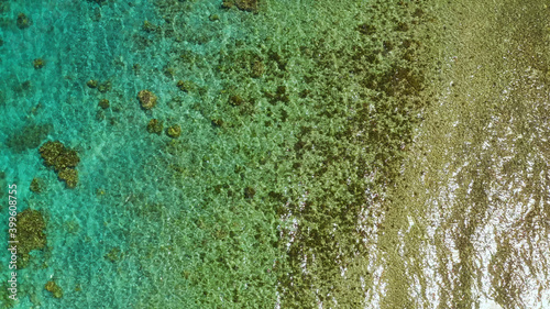 Sea water surface in lagoon, background with sun, copy space for text, aerial view. Top view transparent turquoise ocean water surface. background texture