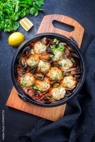 Traditional Norwegian fish ball fiskeboller with fish and mussels in red wine sauce as close-up in a modern design pot