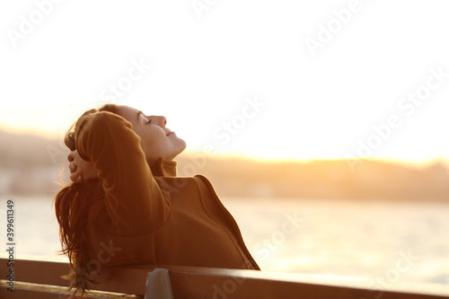 Woman relaxing on a bench in winter on the beach