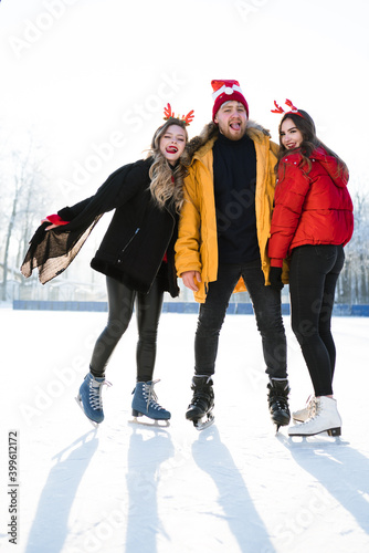 Three young people in bright jackets joyfully skate in winter enjoying the weather
