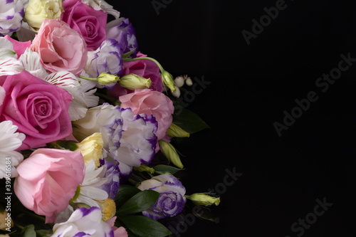 floral arrangement of roses, lisianthus, daisies, chrysanthemums on a black isolated background with free space for text.