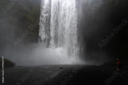 photo at the Skógafoss waterfall where you can see a tourist taking a photo with his mobile