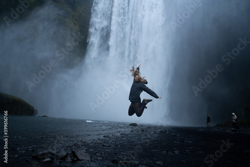 happy girl jumping in the waterfall of Skógafoss iceland