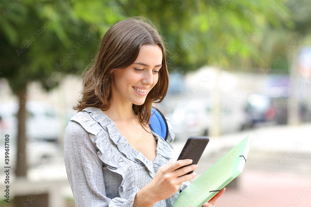Happy student checks smart phone in the street Happy student checks smart phone in the street