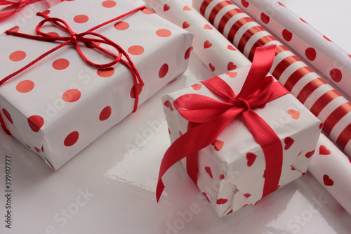 Red and white gift box with ribbon and wrapping paper. Overhead view of table with present preparation. © Juver