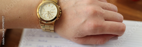 Woman's hand with watch pen next to it lies diary. Working time scheduling at remote work concept