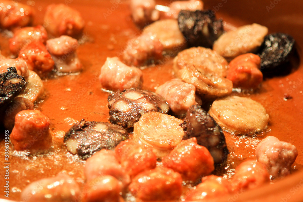 Traditional Spanish sausages frying in a clay pot Traditional Spanish sausages frying in a clay pot