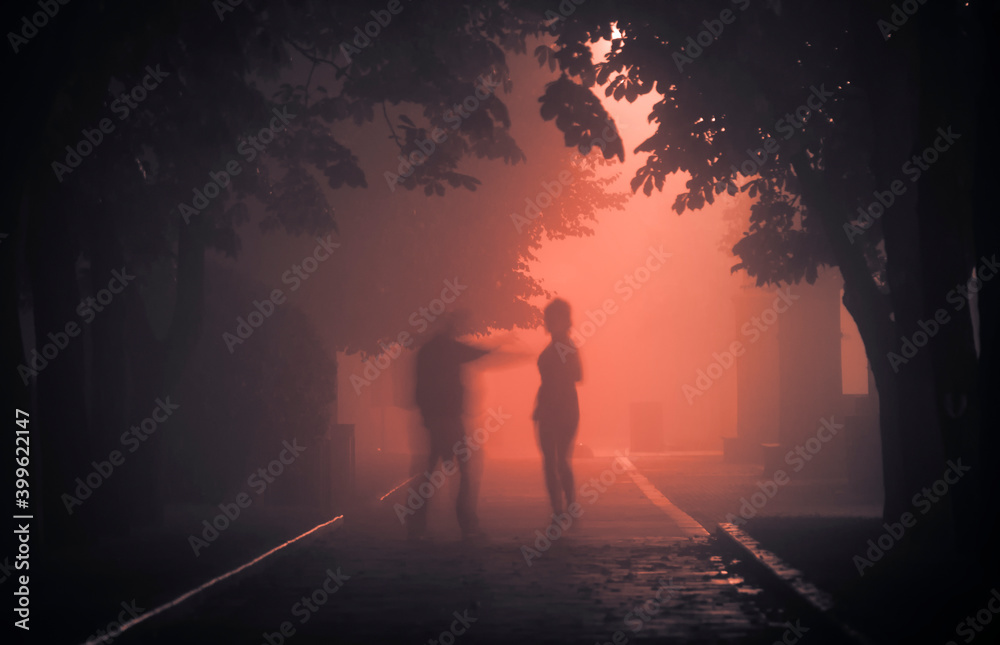 Fototapeta premium A maniac on a foggy street at night attacks a passerby.