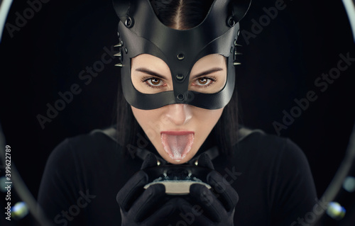 a woman in a black body belt and cat mask with a bowl of milk