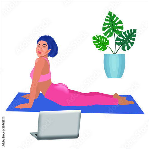 Beautiful sporty woman in yoga cobra pose doing exersice watching video online on computor at home during isolation. Concept of online lessons or yoga studio classes with instructor, social media post