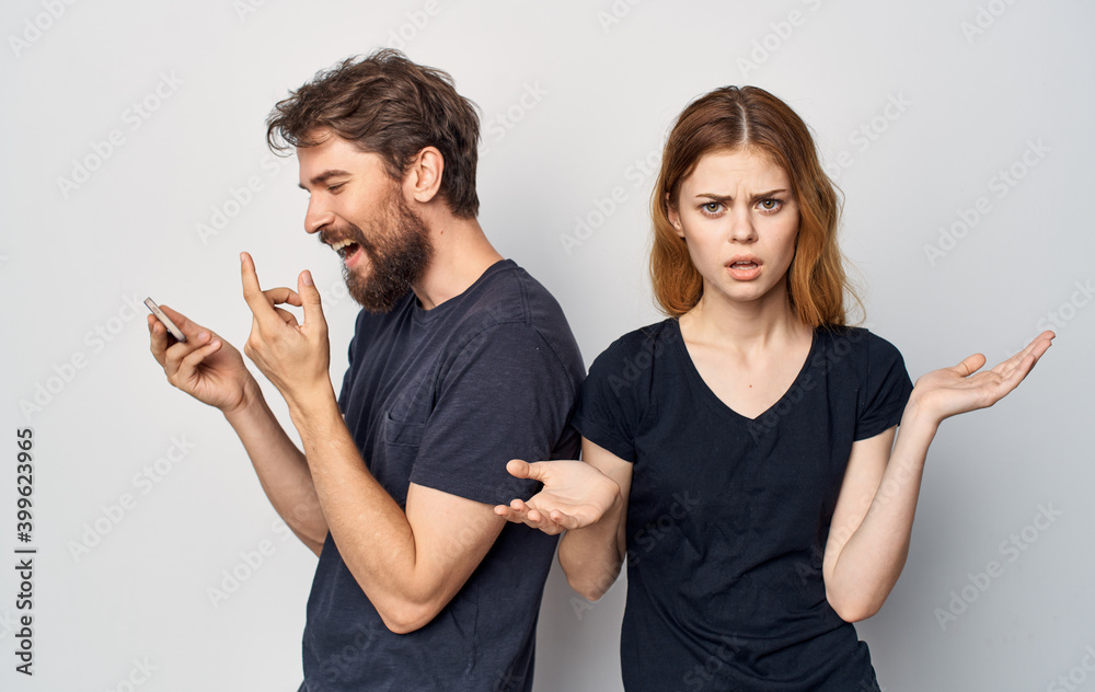 young couple in black t-shirts with phone communicating dissatisfaction lifestyle young couple in black t-shirts with phone communicating dissatisfaction lifestyle