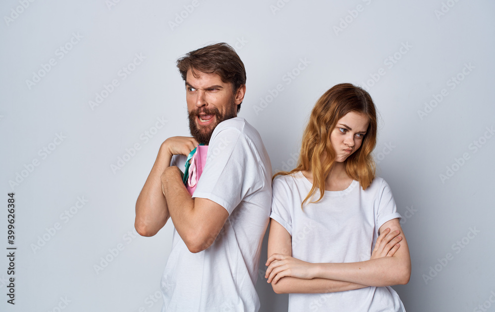 offended woman turned away from a man with gift bags on a light background offended woman turned away from a man with gift bags on a light background