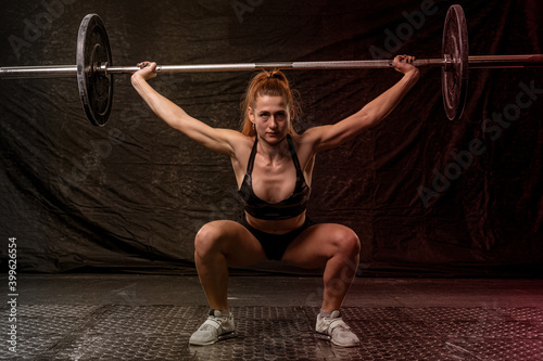 girl athlete in a squat raises a barbell above her head