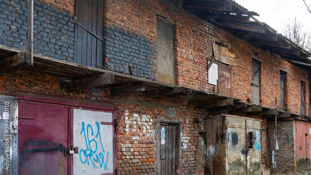 Old rusty iron gate with red brick wall loft warehouse. Slum concept. Background for design. Space for text. Old rusty iron gate with red brick wall loft warehouse. Slum concept. Background for design. Space for text.