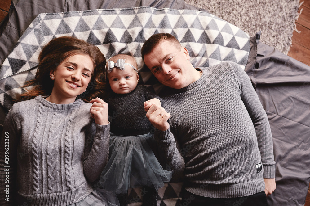 Obraz premium High angle view of a couple of attractive young parents lying in a bed with their cute baby girl. happy holiday.