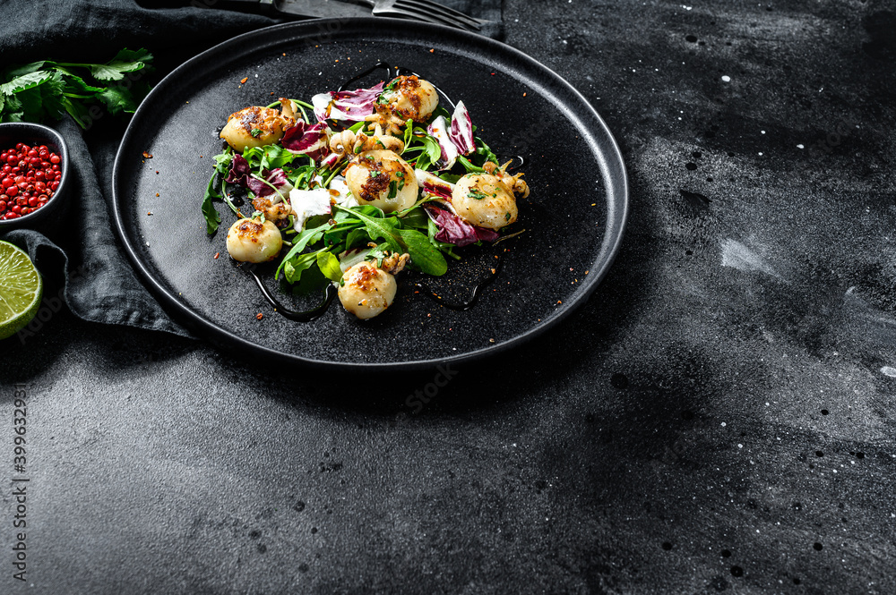 Salad with grilled cuttlefish and arugula. Black background. Top view. Copy space