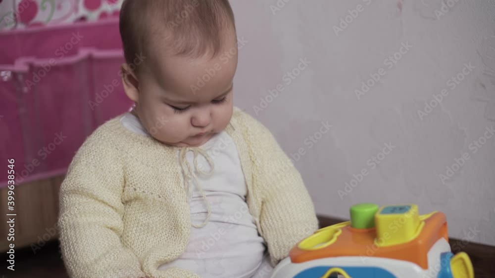 infant, childhood concept - happy funny playfull toddler kid 8 month baby girl sit playing Car Shape Sorter on mat. chubby active awake gnaws toys her teeth cut on floor in playroom indoors at home